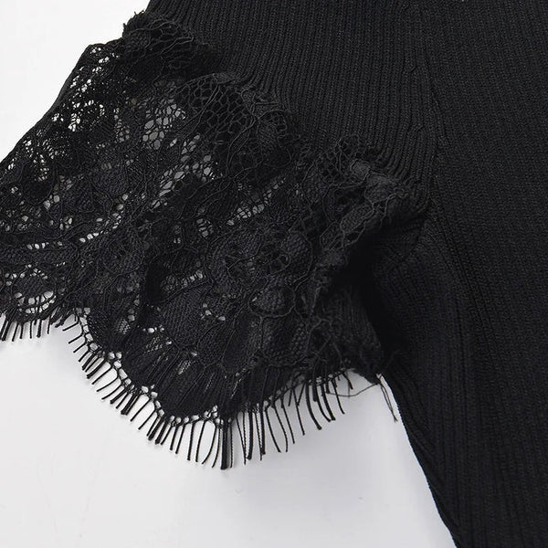 Close-up of a black ribbed knit garment with a wide black lace ruffle and fringe trim on a plain white background.